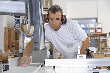 Deutschland, Oberbayern, Schaeftlarn, Schreiner bei der Arbeit an einer Sägemaschine - TCF001869