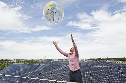Deutschland, München, Älterer Mann mit Globus in Solaranlage - WESTF017864