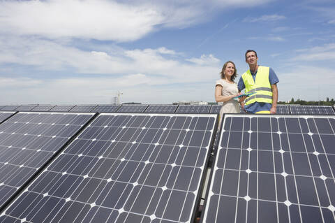 Deutschland, München, Ingenieure stehen in Solaranlage, lächelnd, lizenzfreies Stockfoto