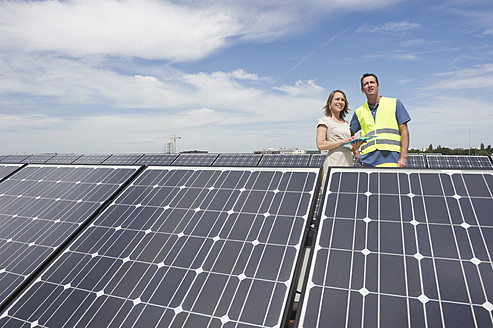 Deutschland, München, Ingenieure stehen in Solaranlage, lächelnd - WESTF017884