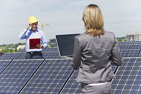 Deutschland, München, Ingenieure mit Laptop und Besprechung in einer Solaranlage - WESTF017887