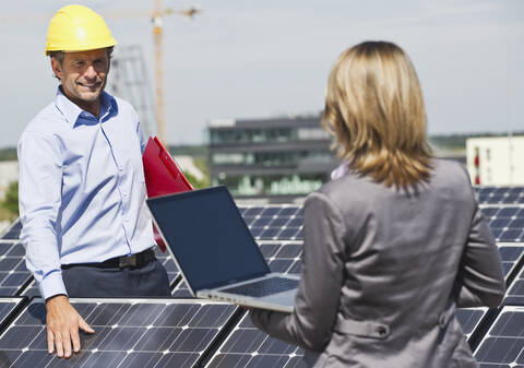 Deutschland, München, Ingenieure mit Laptop und Besprechung in einer Solaranlage, lizenzfreies Stockfoto