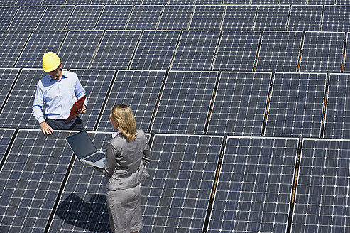 Deutschland, München, Ingenieure mit Laptop und Besprechung in einer Solaranlage - WESTF017892