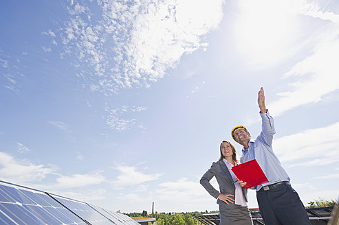 Deutschland, München, Ingenieure mit Klemmbrett in Solaranlage, lächelnd - WESTF017894