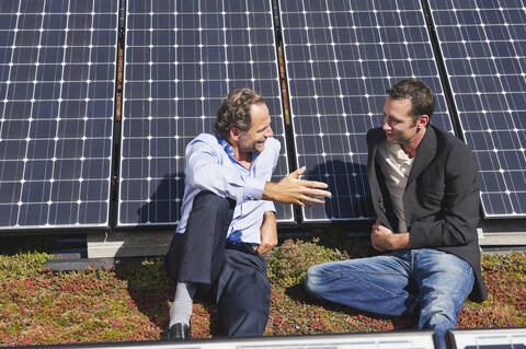 Deutschland, München, Zwei Männer sitzen und reden in einer Solaranlage, lizenzfreies Stockfoto