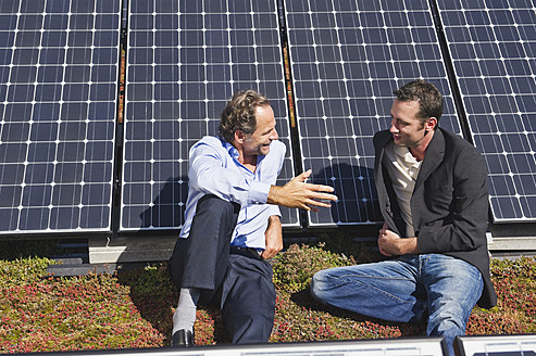 Deutschland, München, Zwei Männer sitzen und reden in einer Solaranlage - WESTF017897