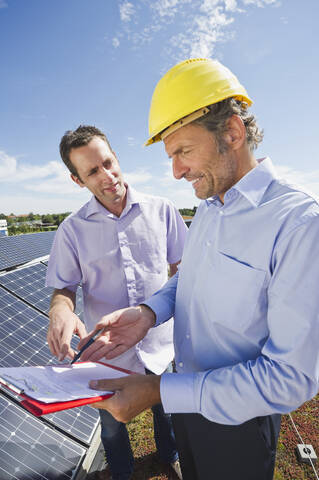 Deutschland, München, Mann diskutiert mit Ingenieur in Solaranlage, lizenzfreies Stockfoto