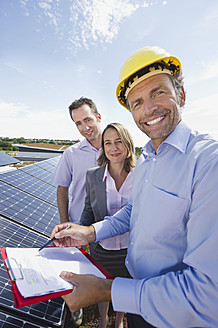 Deutschland, München, Ingenieur mit Mann und Frau in Solaranlage, lächelnd, Porträt - WESTF017909