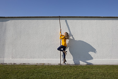 Deutschland, Bayern, München, Junge Frau klettert an Wand mit Seil - RBF000730