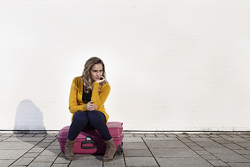 Deutschland, Bayern, München, Junge Frau sitzt auf Koffer - RBF000742