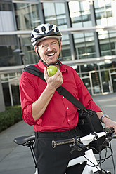 Deutschland, Bayern, Älterer Mann auf Fahrrad mit Obst, Porträt, lächelnd - RNF000677