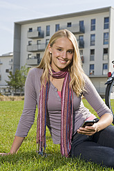 Deutschland, Bayern, Teenager-Mädchen sitzt mit Fahrrad im Gras, lächelnd, Porträt - RNF000691