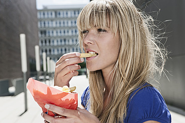 Eine junge Frau genießt Pommes Frites in Köln, Deutschland - WESTF017945