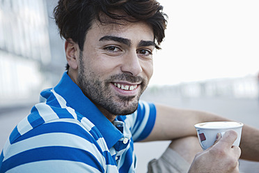 Porträt eines jungen Mannes aus Köln, der lächelnd eine Kaffeetasse hält - WESTF017972