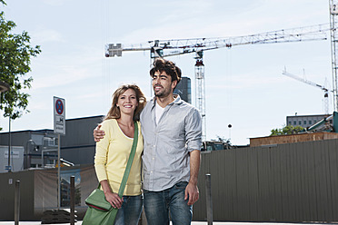 A happy young couple poses in front of a construction site in Cologne, Germany - WESTF017992