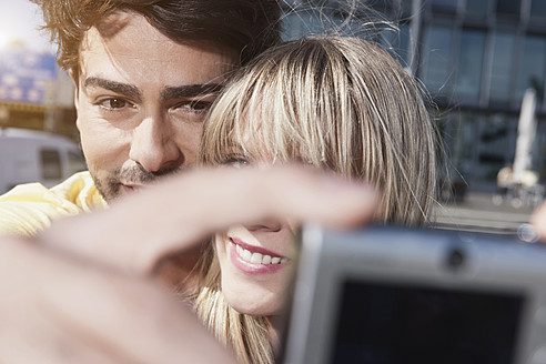 Junges Paar aus Köln lächelt und benutzt ein Handy für ein Selfie - WESTF018012