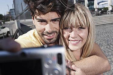 A happy young couple in Cologne, Germany, snap a photo using their cell phone and share a smile - WESTF018013