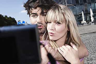 A young couple in Cologne, Germany, snap a photo using their cell phone to capture the moment - WESTF018014