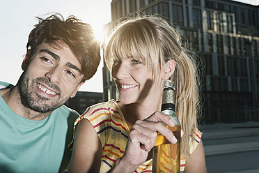 A happy young couple in Cologne, Germany, enjoying a refreshing beer together with big smiles on their faces - WESTF018030