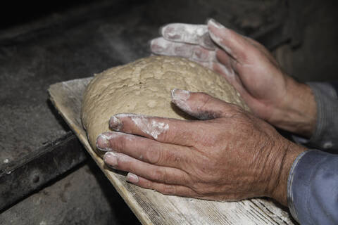 Senior Mann beim Brotbacken in traditioneller Holzofenbäckerei in Egling, Oberbayern, Deutschland, lizenzfreies Stockfoto