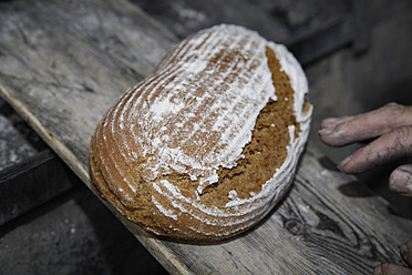 An elderly man in Egling, Upper Bavaria, Germany, bakes bread in a traditional wood stove bakery - TCF001937