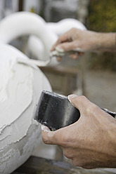 A sculptor in Schaeftlarn, Upper Bavaria, Munich, applies plaster with a trowel to create a masterpiece - TCF001984