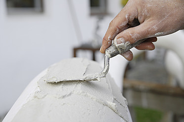 A sculptor in Schaeftlarn, Upper Bavaria, Munich, applies plaster with a trowel to create a masterpiece - TCF001986