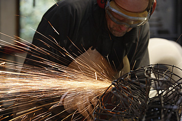 A sculptor in Schaeftlarn, Upper Bavaria, Munich, using an abrasive cutting tool to shape his creation. - TCF001997