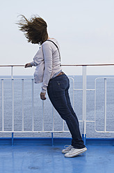 Eine Frau im mittleren Erwachsenenalter genießt die Aussicht, während sie auf dem Deck eines Bootes in Ithaka auf den Ionischen Inseln in Griechenland steht - MUF001129