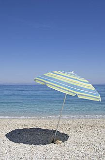 Genießen Sie einen ruhigen Strandtag auf Ithaka, einer der atemberaubenden Ionischen Inseln Griechenlands, unter einem bunten Sonnenschirm - MUF001145