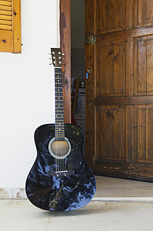 Eine malerische Szene in Ithaka, Griechenland, mit einer Gitarre, die neben einer offenen Tür liegt und zu Musik und Entspannung einlädt - MUF001169