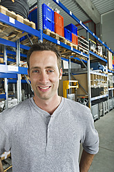 A cheerful worker smiles for the camera in a Munich warehouse, Bavaria, Germany - WESTF018042