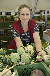 In Wolfratshausen, Oberbayern, Deutschland, wählt eine Frau auf einem lokalen Markt mit großer Sorgfalt hochwertige Produkte aus - TCF002103