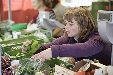 A woman selects fresh produce from a bustling market in Wolfratshausen, Upper Bavaria, Germany - TCF002126