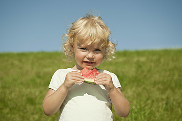 Ein junges bayerisches Mädchen genießt ein erfrischendes Stück Wassermelone inmitten einer atemberaubenden Landschaft - RNF000731