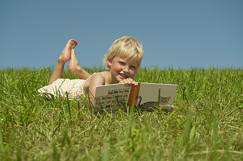 A peaceful moment in Bavaria as a young girl loses herself in a book, surrounded by the serene beauty of nature - RNF000749