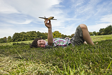 Cheerful young boy enjoying a playful day in a Bavarian park, piloting a model airplane with a big smile - SKF000547