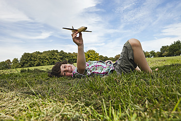Fröhlicher Junge, der einen spielerischen Tag in einem bayerischen Park genießt und mit einem breiten Lächeln ein Modellflugzeug steuert - SKF000547