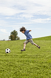 Ein kleiner Junge spielt fröhlich Fußball in einem malerischen Park in Bayern, Deutschland - SKF000550