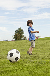 Ein kleiner Junge genießt ein Fußballspiel inmitten der atemberaubenden Schönheit der bayerischen Parklandschaft in Deutschland - SKF000551