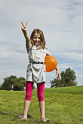Ein glückliches kleines Mädchen spielt mit einem Luftballon in einem bayerischen Park und genießt die einfachen Freuden der Kindheit. - SKF000554