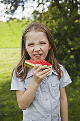 A picturesque portrait of a young girl enjoying a delicious watermelon slice in a beautiful Bavarian park - SKF000560