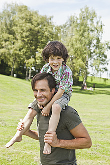Ein glücklicher bayerischer Vater nimmt seinen Sohn bei einem vergnüglichen Ausflug in den Park huckepack - SKF000567