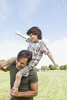 Ein glücklicher bayerischer Vater nimmt seinen Sohn während eines herrlichen Tages im Park huckepack - SKF000571