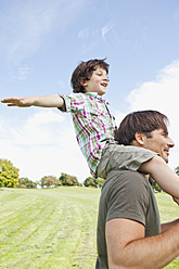 Ein glücklicher bayerischer Vater nimmt seinen Sohn während eines herrlichen Tages im Park huckepack - SKF000572