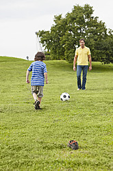 Father and son bonding over soccer in picturesque Bavarian park, strengthening their relationship through sport - SKF000579