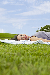 A young woman basks in the warm sun, unwinding on a cozy blanket amidst the stunning scenery of Bavarian park - SKF000583