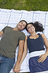 Ein fröhliches Paar, das sich in der Ruhe eines bayerischen Parks auf einer gemütlichen Decke ausruht und vor Freude strahlt - SKF000586