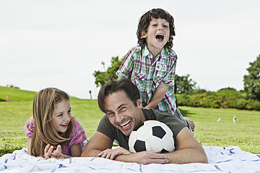 A joyful Bavarian family spending a leisurely day in the park, basking in the sun on a cozy picnic blanket - SKF000596