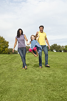 Eine bayerische Familie, die sich im Park vergnügt, wobei die Eltern spielerisch mit ihrer Tochter interagieren und eine schöne Zeit verbringen - SKF000600